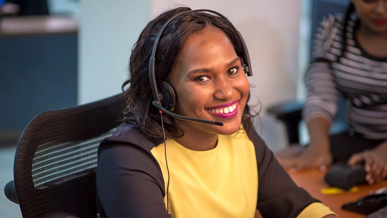 Collaboratrice souriante au téléphone avec un client