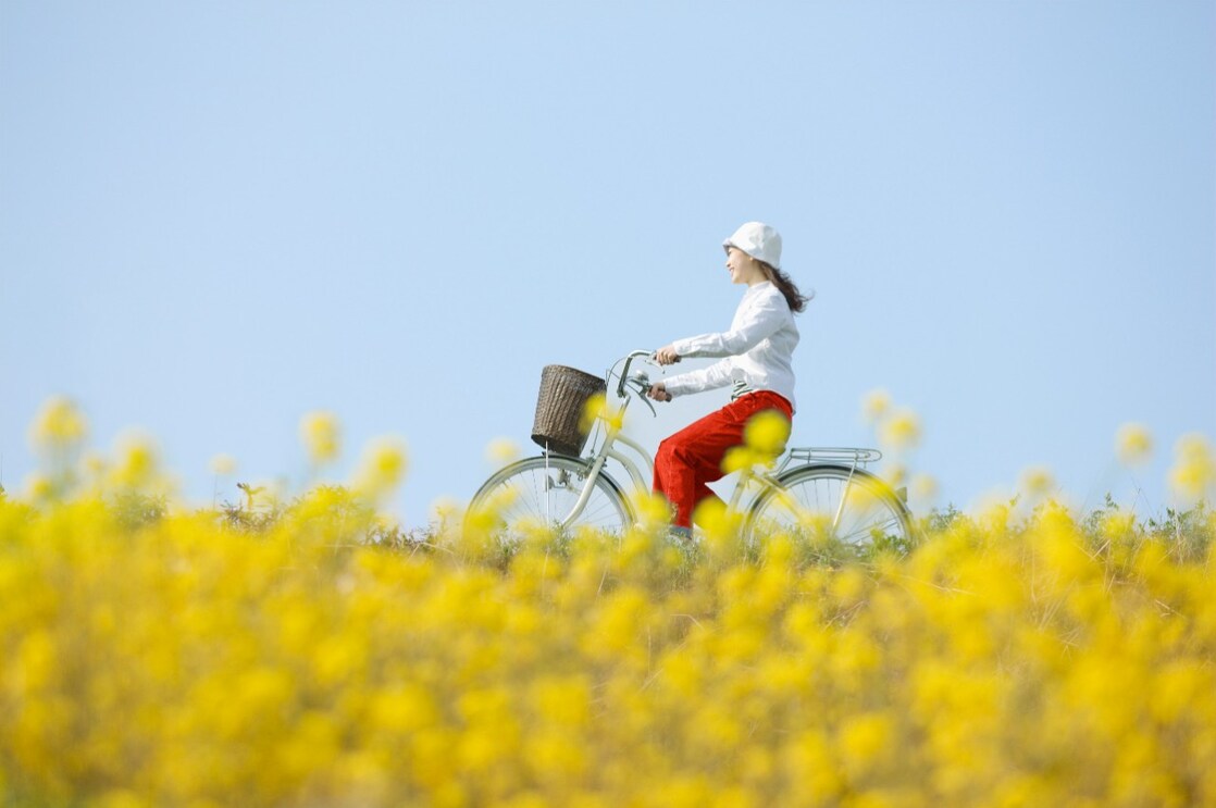 Une jeune femme fait une balade à vélo dans un champ en fleurs en été