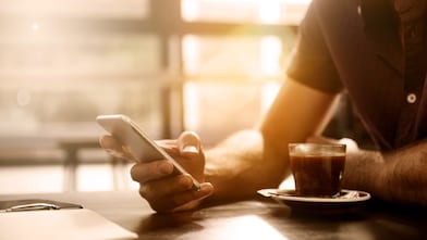 Homme prenant un café tout en consultant son smartphone