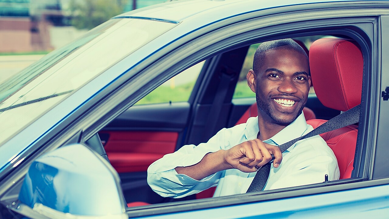 man putting on seat belt in a car