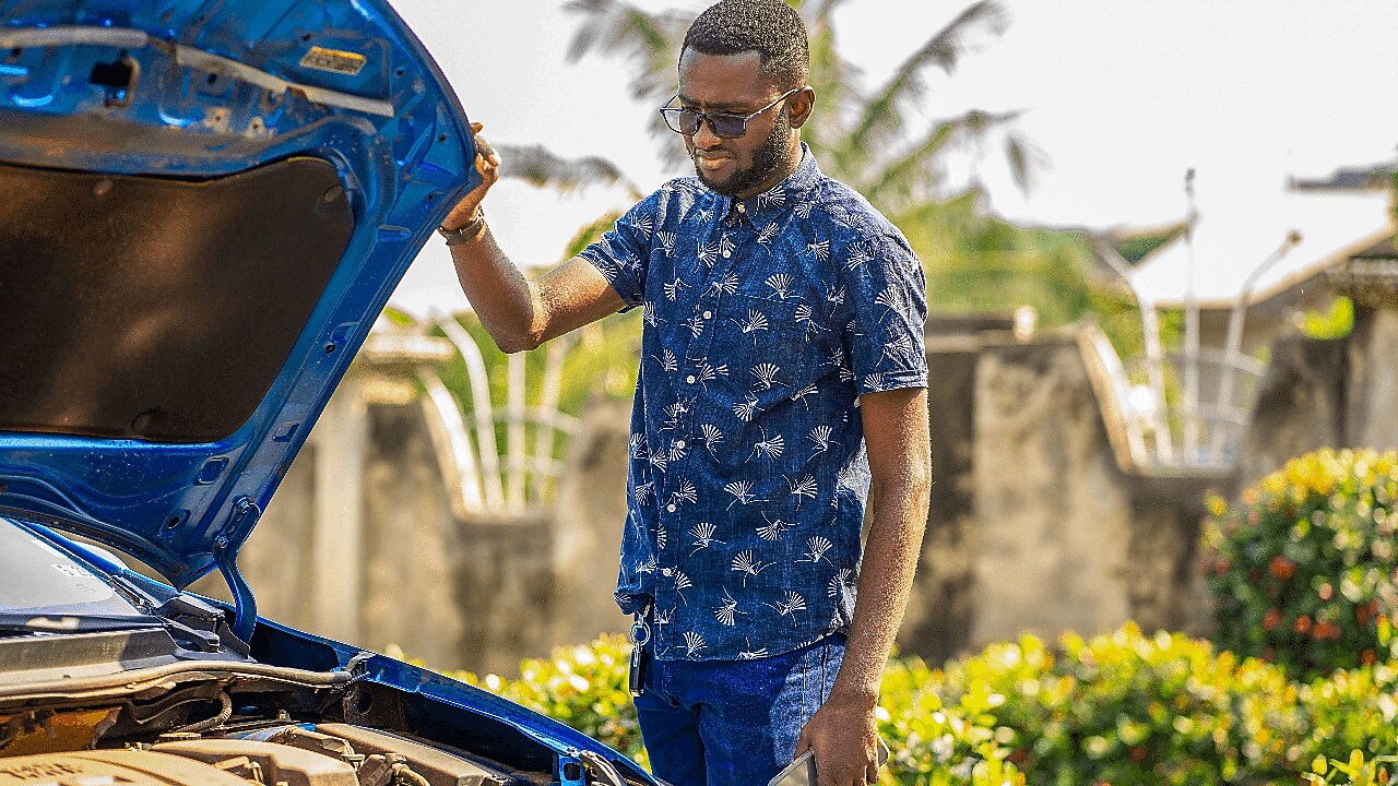 Un automobiliste vérifiant l'état de son moteur sur la route